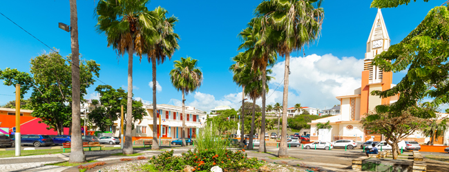 Blick auf das Stadtzentrum von Sainte Anne auf Guadeloupe mit Palmen und einer Kirche während einer Sprachreise