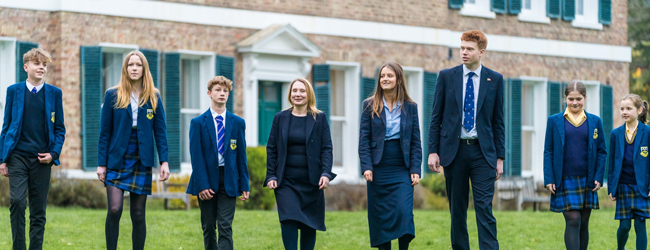 Vor einer High School in England stehen Schüler in Uniform Schüler in Schuluniform stehen vor ihrer High School in England